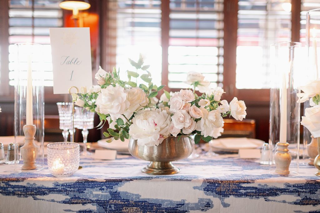 Detail shot of table number and white flower centerpiece with blue design table clothe