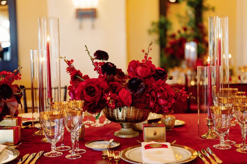 Detail shot of red flower centerpiece and gold lined dishware