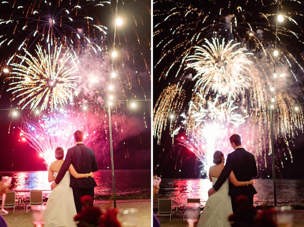 Bride and Groom holding each other watching fireworks on the water