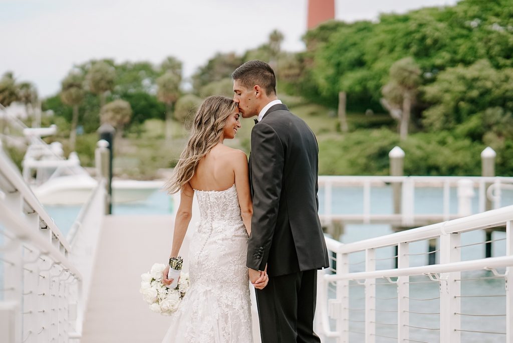 Groom kissing Bride on forehead on the dock