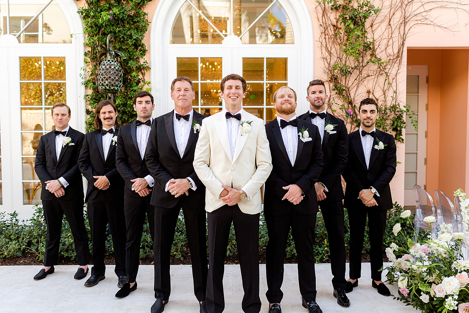 Groom wearing white jacket in formation with Groomsmen in triangle position
