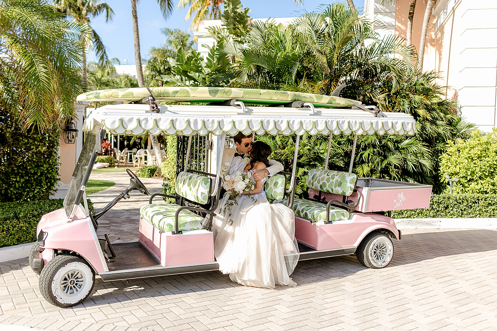 Bride and Groom kissing in Bright extended pink golf cart 