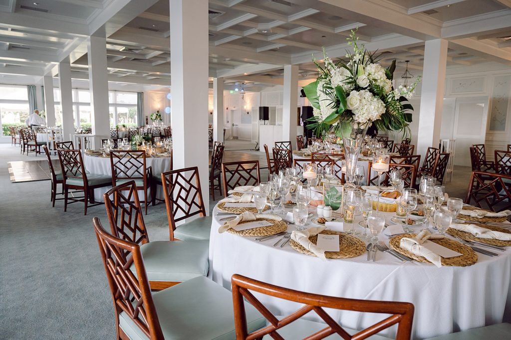 Detail shot of round Reception tables with tropical floral centerpieces with brown chairs